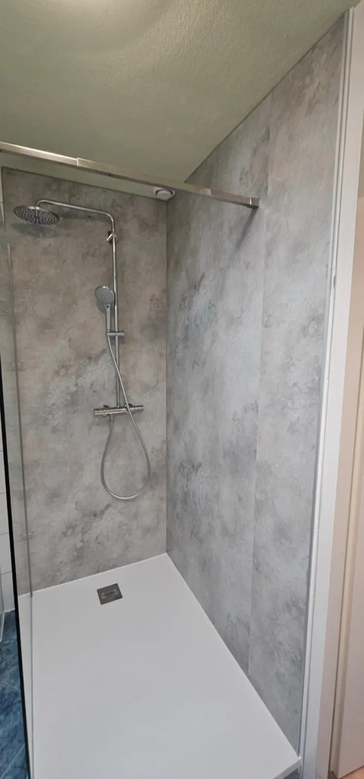 Nieuwe, drempelloze inloopdouche met moderne grijze wandpanelen en witte antislip douchebak, geïnstalleerd door SaniSafe.