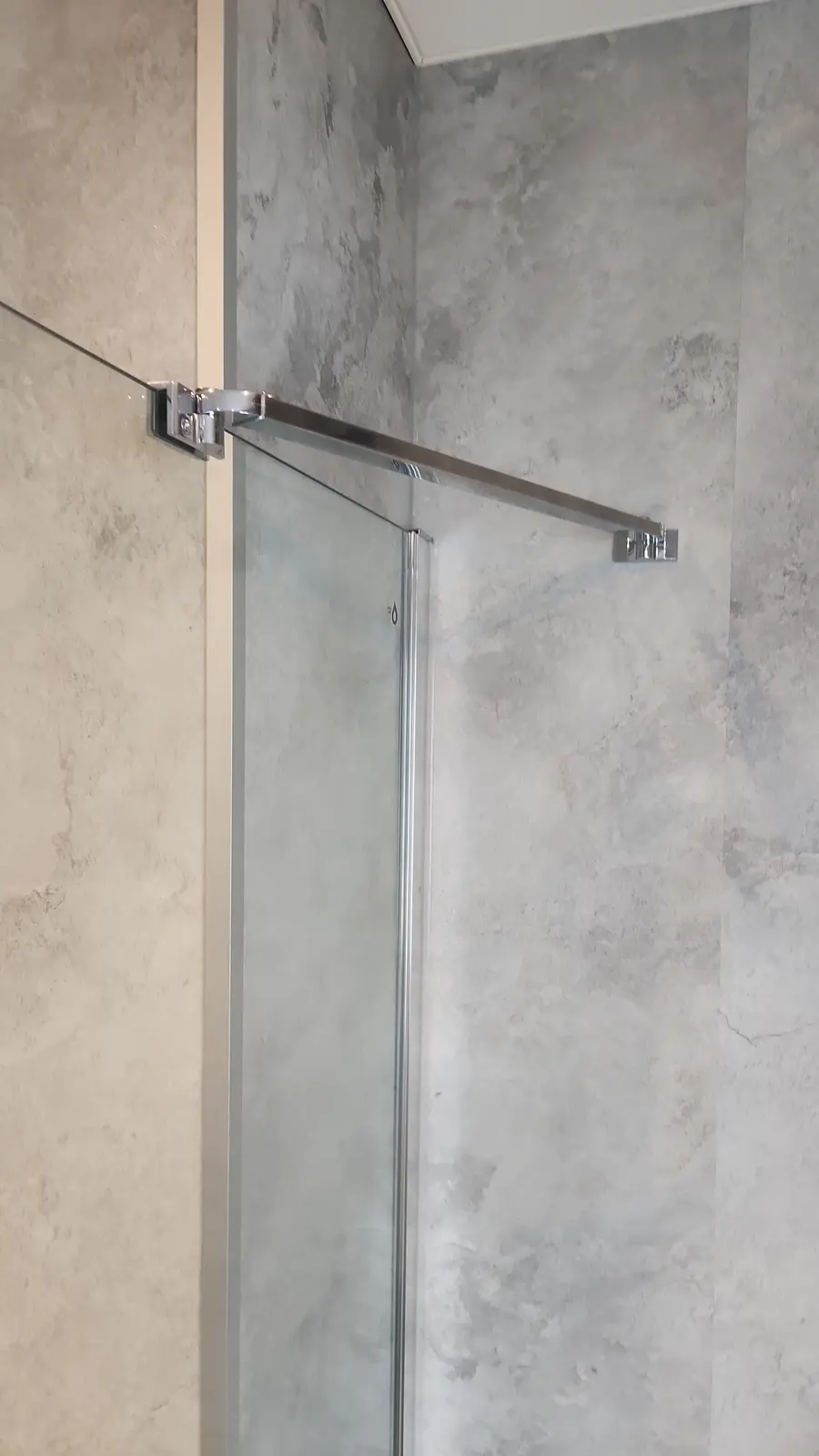 Detail van een moderne inloopdouche met glazen deur en chromen afwerking in een SaniSafe badkamer.